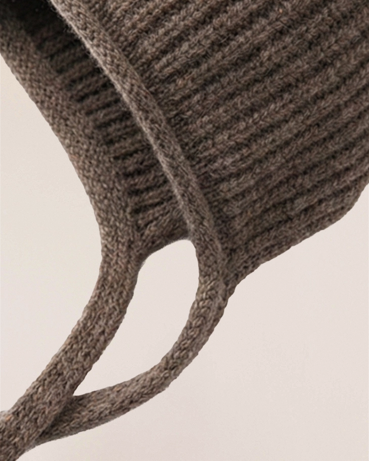 Close-up of VIONIS·XY cocoa merino bonnet ties, elongated soft knit for adjustable styling