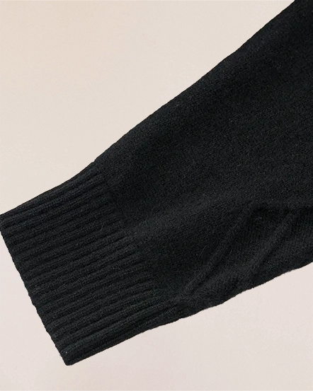 Sleeve detail of VIONIS·XY black cashmere sweater, smooth ribbed cuff in heavy-weight knit